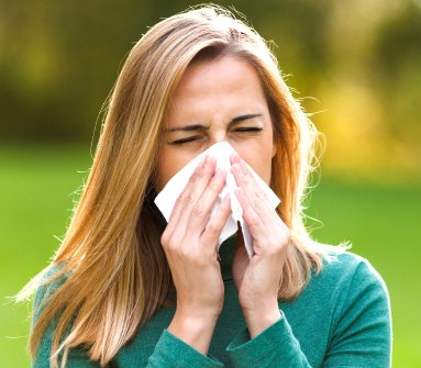 Woman sneezing into a tissue